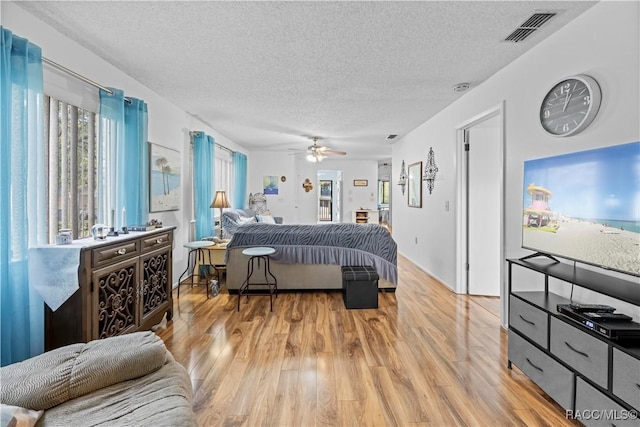 bedroom featuring a textured ceiling, ceiling fan, and light hardwood / wood-style flooring