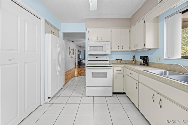 kitchen with sink, a textured ceiling, white cabinetry, white appliances, and light tile patterned floors