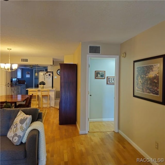 living room featuring a textured ceiling, light hardwood / wood-style floors, and a chandelier