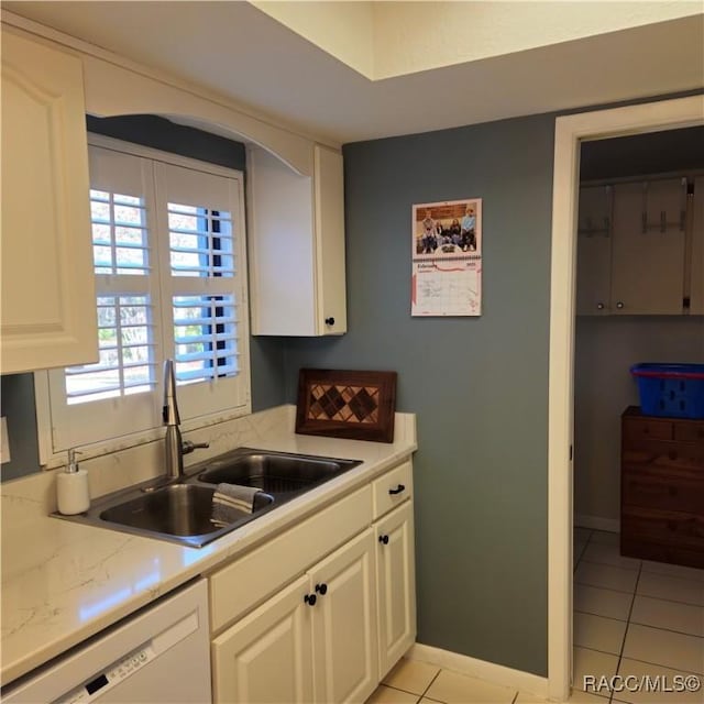 kitchen with white cabinetry, sink, light tile patterned floors, and white dishwasher