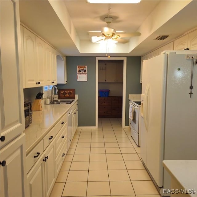 kitchen with sink, white appliances, light tile patterned floors, white cabinetry, and a raised ceiling