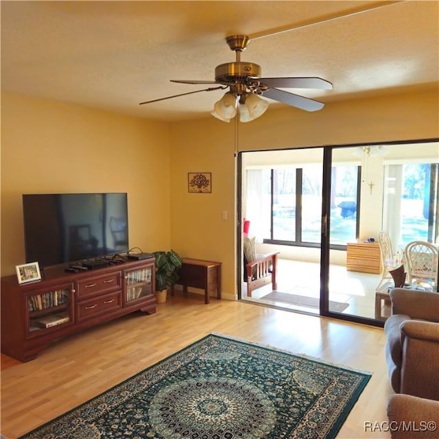 living room with ceiling fan, plenty of natural light, and wood-type flooring