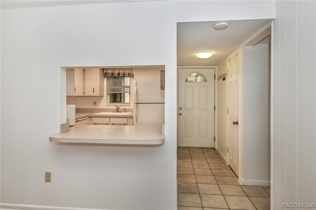 kitchen featuring sink, a textured ceiling, white refrigerator, and light tile patterned flooring