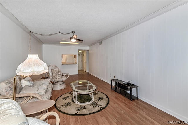 living room featuring ceiling fan, hardwood / wood-style floors, a textured ceiling, and ornamental molding