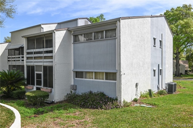 view of side of property featuring cooling unit and a lawn