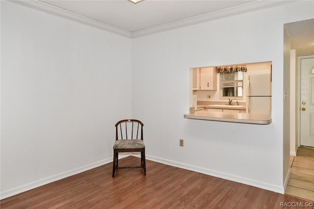 sitting room with sink, wood-type flooring, and crown molding