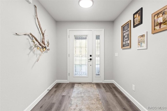 doorway to outside with wood finished floors and baseboards