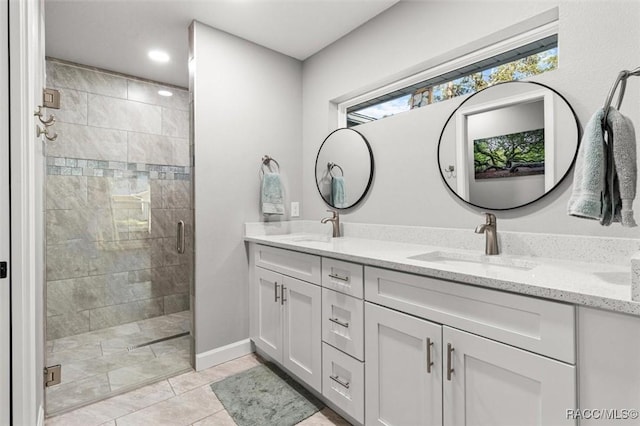 bathroom featuring a tile shower, double vanity, baseboards, and tile patterned flooring