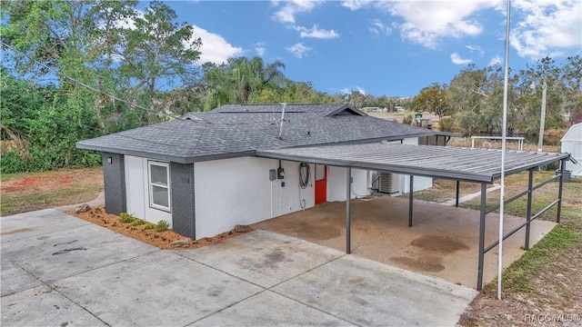 exterior space featuring a carport, a shingled roof, driveway, and stucco siding