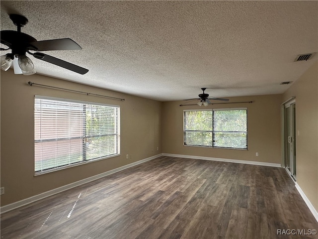 empty room featuring a textured ceiling, ceiling fan, and dark wood-type flooring