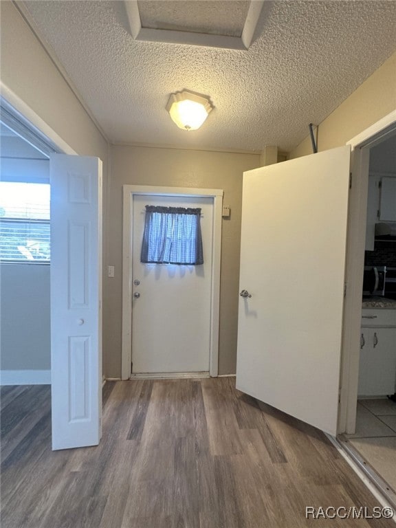 doorway with a textured ceiling and hardwood / wood-style flooring