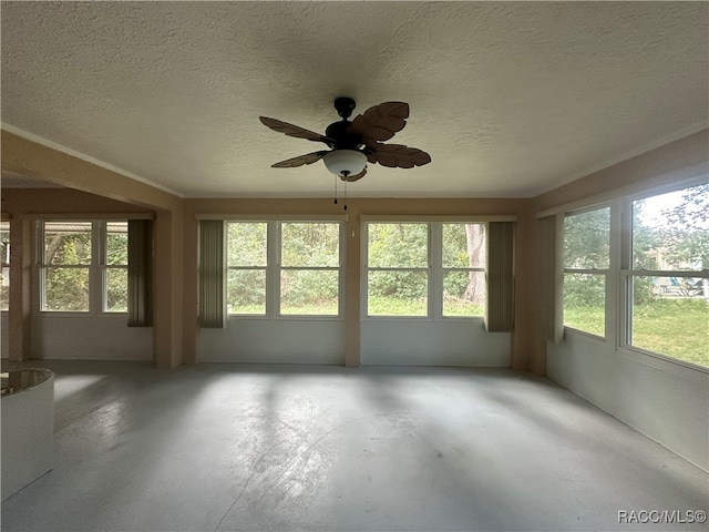 unfurnished sunroom featuring ceiling fan and plenty of natural light