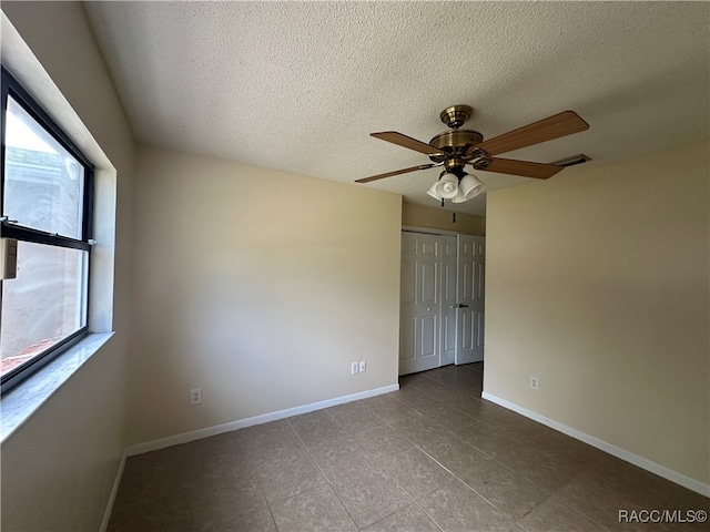 unfurnished room with ceiling fan, a healthy amount of sunlight, and a textured ceiling