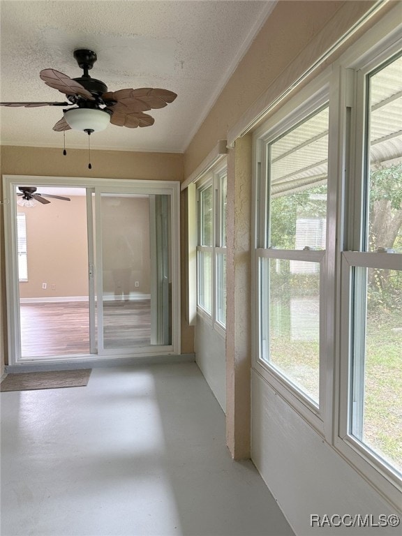 unfurnished sunroom featuring ceiling fan and a healthy amount of sunlight