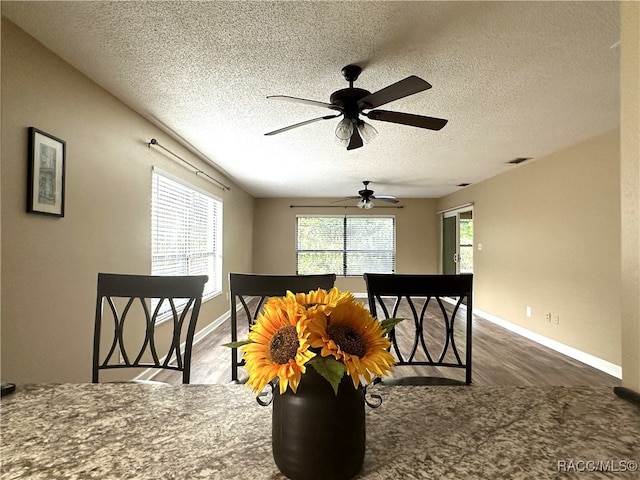 dining room featuring a textured ceiling, ceiling fan, and dark wood-type flooring