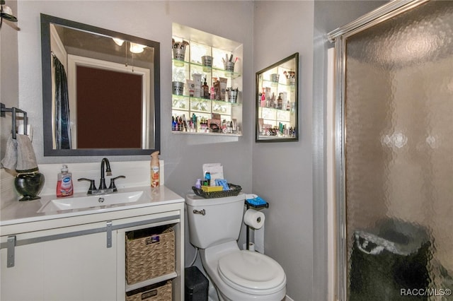 bathroom with vanity, toilet, and a shower with door