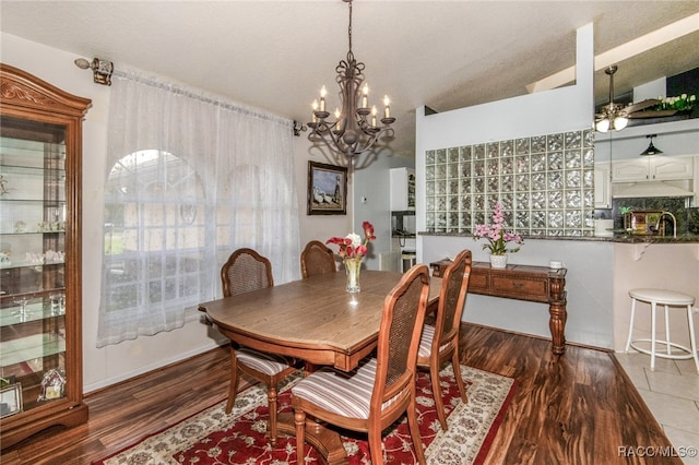 dining space featuring ceiling fan with notable chandelier, wood-type flooring, and vaulted ceiling