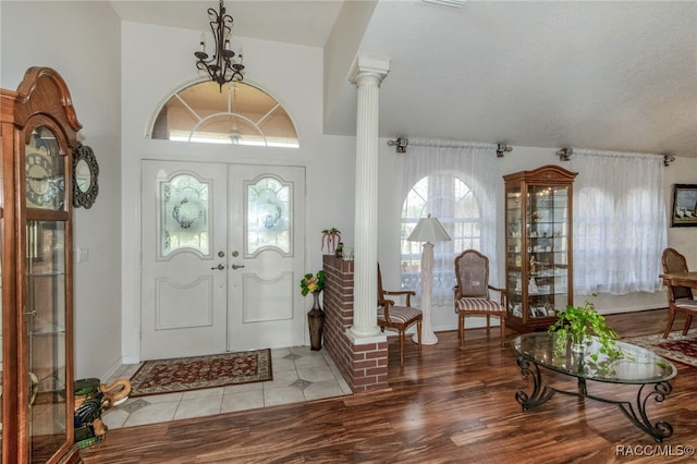 entryway with ornate columns, french doors, and light hardwood / wood-style floors