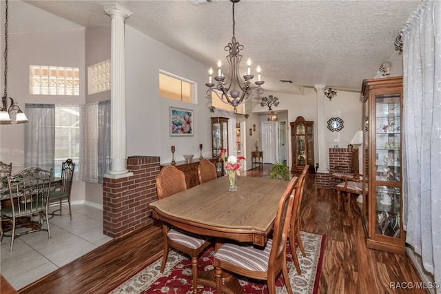 dining area with ornate columns, a textured ceiling, vaulted ceiling, wood-type flooring, and a notable chandelier