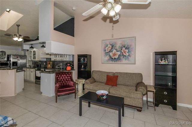 tiled living room featuring a skylight, high vaulted ceiling, and ceiling fan