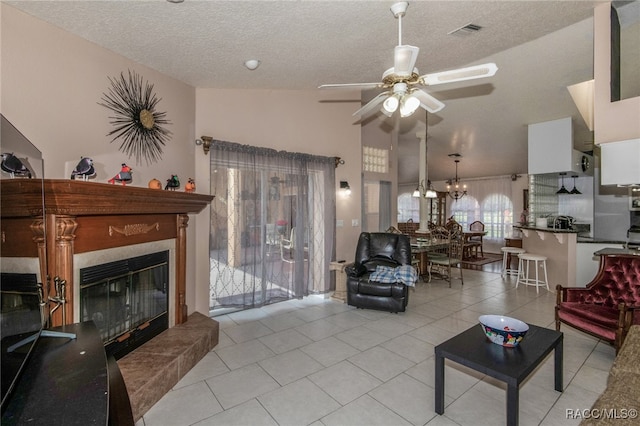 tiled living room featuring ceiling fan with notable chandelier, a textured ceiling, vaulted ceiling, and a tiled fireplace