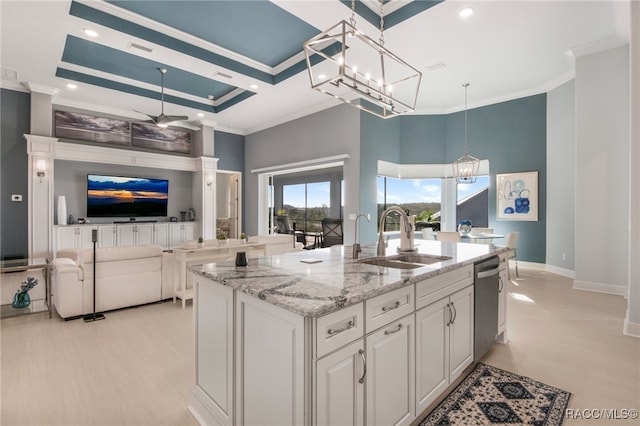 kitchen with light stone countertops, a kitchen island with sink, sink, pendant lighting, and white cabinets