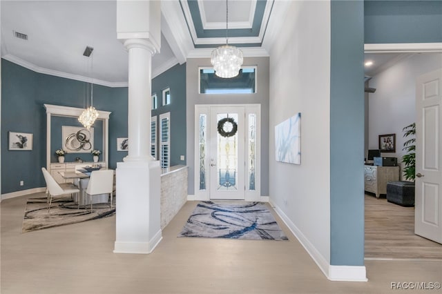 foyer with decorative columns, light hardwood / wood-style floors, and a notable chandelier