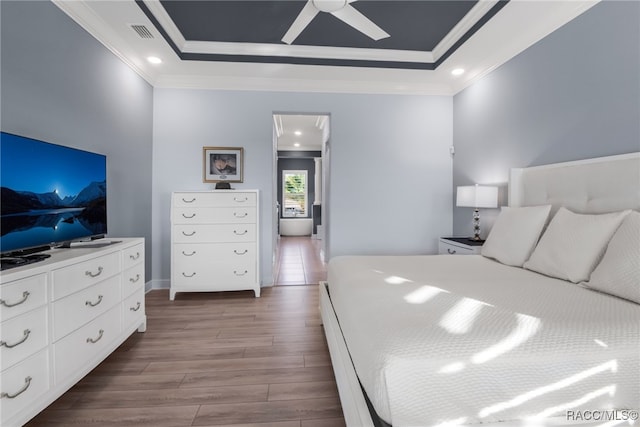 bedroom featuring a raised ceiling, ceiling fan, hardwood / wood-style flooring, and ornamental molding