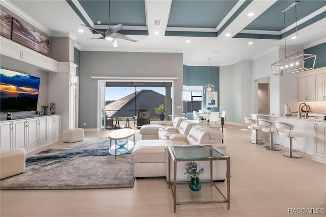 living room featuring ceiling fan with notable chandelier, ornamental molding, sink, and a towering ceiling