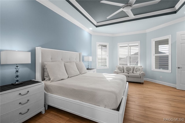 bedroom with a tray ceiling, ceiling fan, light hardwood / wood-style flooring, and ornamental molding