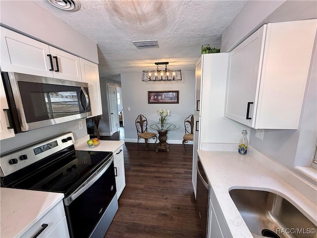 kitchen with white cabinetry, stainless steel appliances, a textured ceiling, and an inviting chandelier