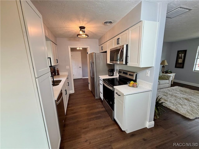 kitchen featuring white cabinetry, dark hardwood / wood-style flooring, a textured ceiling, and appliances with stainless steel finishes