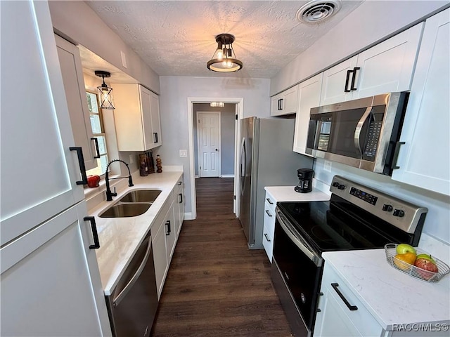 kitchen featuring white cabinets, sink, stainless steel appliances, and hanging light fixtures