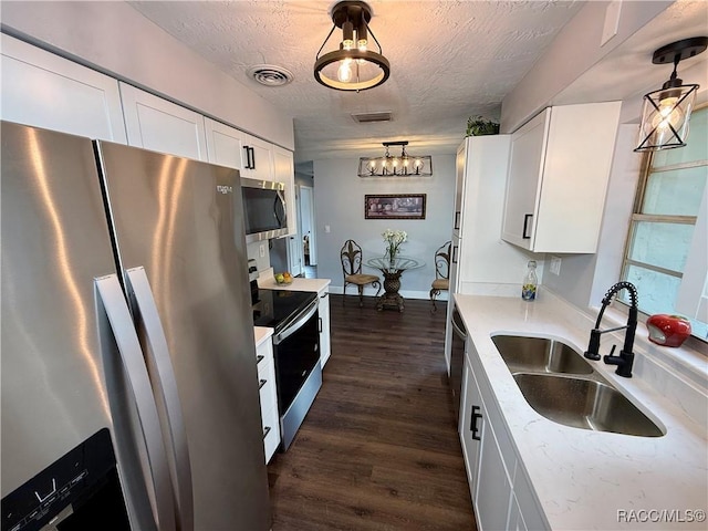 kitchen featuring sink, stainless steel appliances, pendant lighting, a textured ceiling, and white cabinets