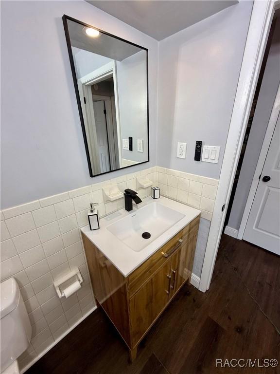 bathroom with vanity, toilet, wood-type flooring, and tile walls