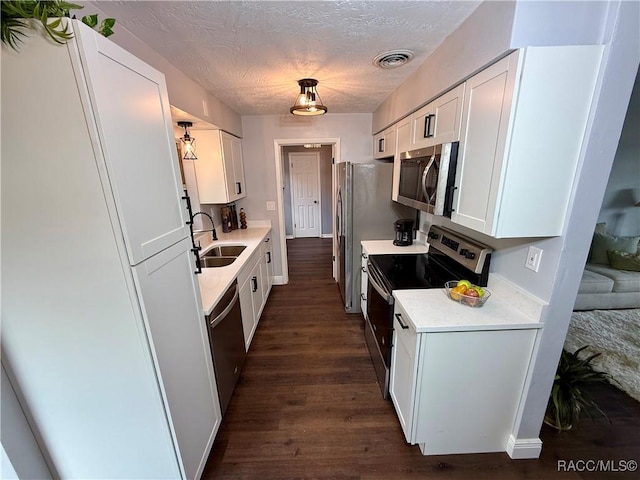 kitchen with white cabinetry, sink, stainless steel appliances, dark hardwood / wood-style flooring, and a textured ceiling