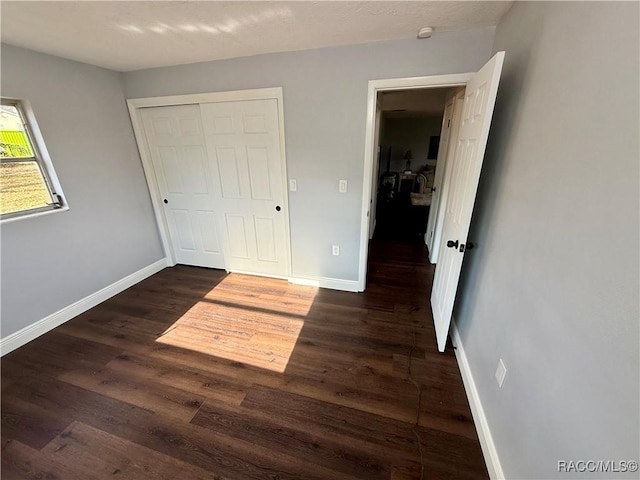 unfurnished bedroom with dark hardwood / wood-style flooring and a closet