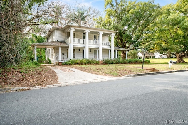 greek revival house featuring a front yard, a balcony, and a porch