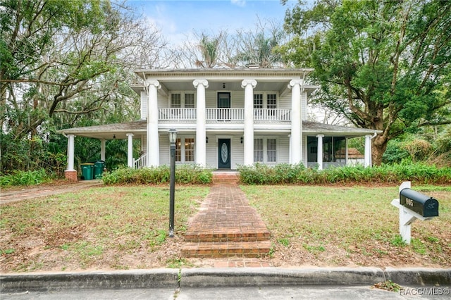 greek revival inspired property featuring a front yard, a balcony, and a porch