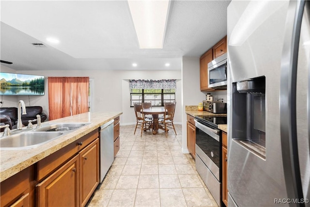 3085 Greynolds Ave, Spring Hill, FL 34608 - kitchen with appliances with stainless steel finishes, brown cabinetry, light tile patterned flooring, open floor plan, and light countertops