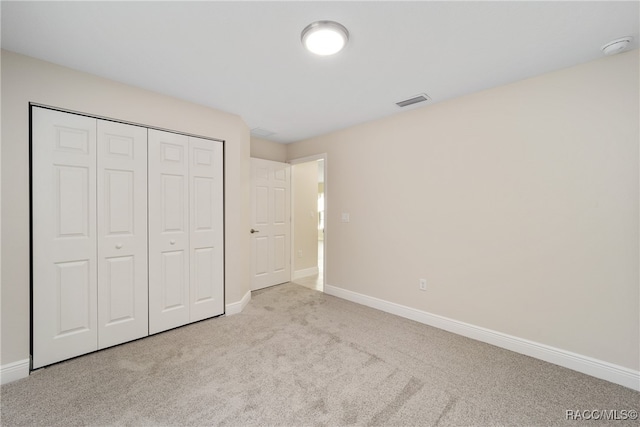 unfurnished bedroom with light carpet and a closet