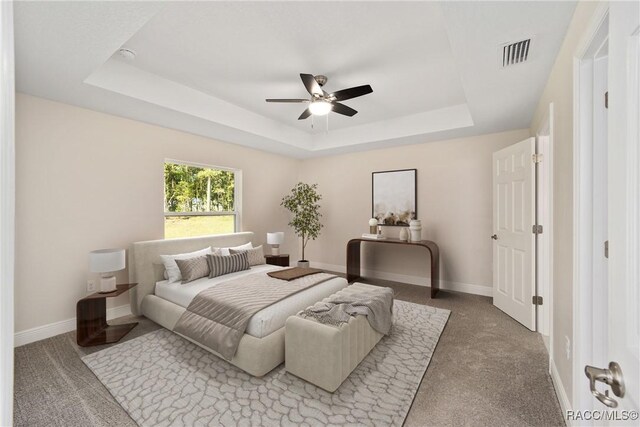 bedroom with ceiling fan, a raised ceiling, and carpet floors