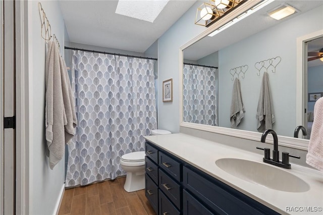 bathroom featuring a skylight, ceiling fan, vanity, and toilet