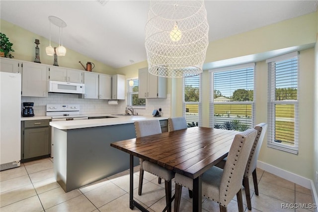 kitchen featuring vaulted ceiling, gray cabinets, white appliances, and decorative light fixtures