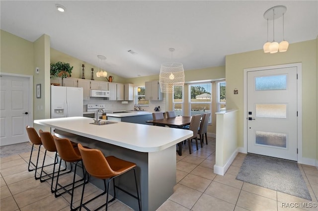 kitchen with decorative light fixtures, a kitchen island, white appliances, and lofted ceiling