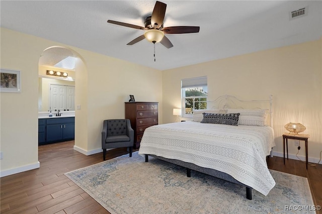 bedroom with ensuite bath, ceiling fan, and hardwood / wood-style floors