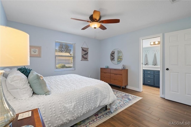 bedroom with ensuite bathroom, ceiling fan, and dark wood-type flooring