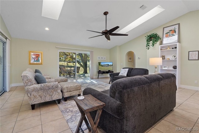 living room with lofted ceiling with skylight, ceiling fan, and light tile patterned flooring