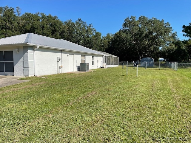 exterior space with central AC unit and a lawn