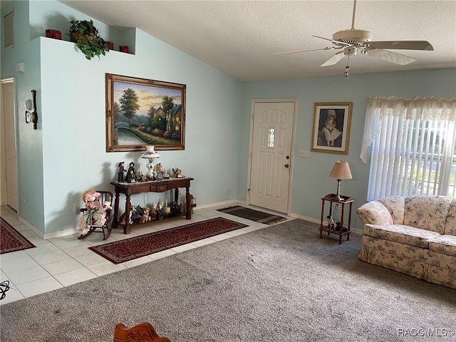 entryway with ceiling fan, light colored carpet, lofted ceiling, and a textured ceiling